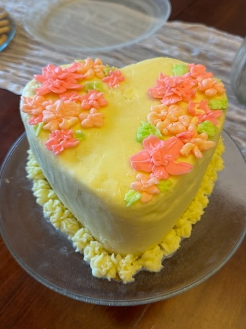 Yellow heart-shaped cake with pink piped flowers