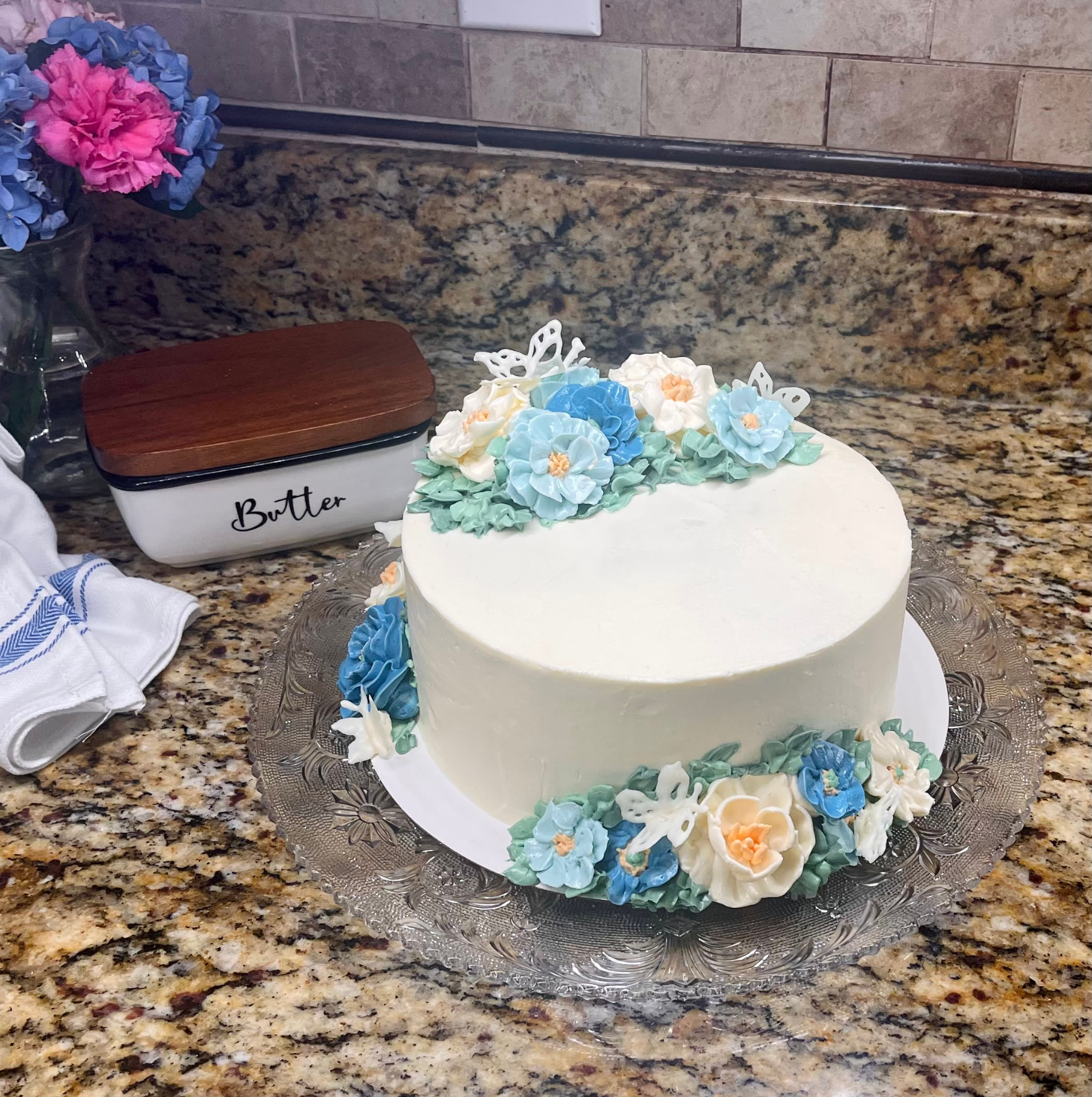 White buttercream cake with blue, peach, and ivory piped flowers